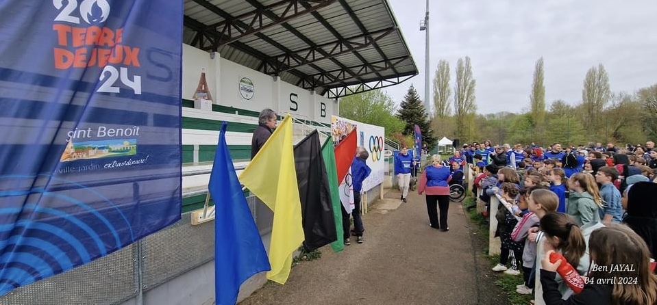participants et organisation regroupés devant drapeaux et anneaux olympiques